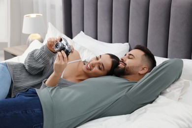 Photo of Happy young couple with camera on bed