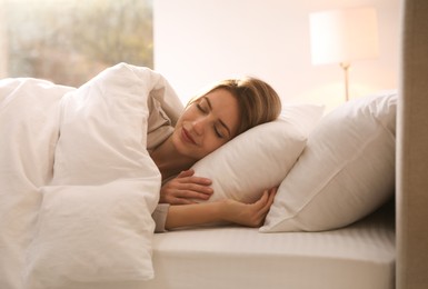 Photo of Woman under warm white blanket sleeping in bed indoors