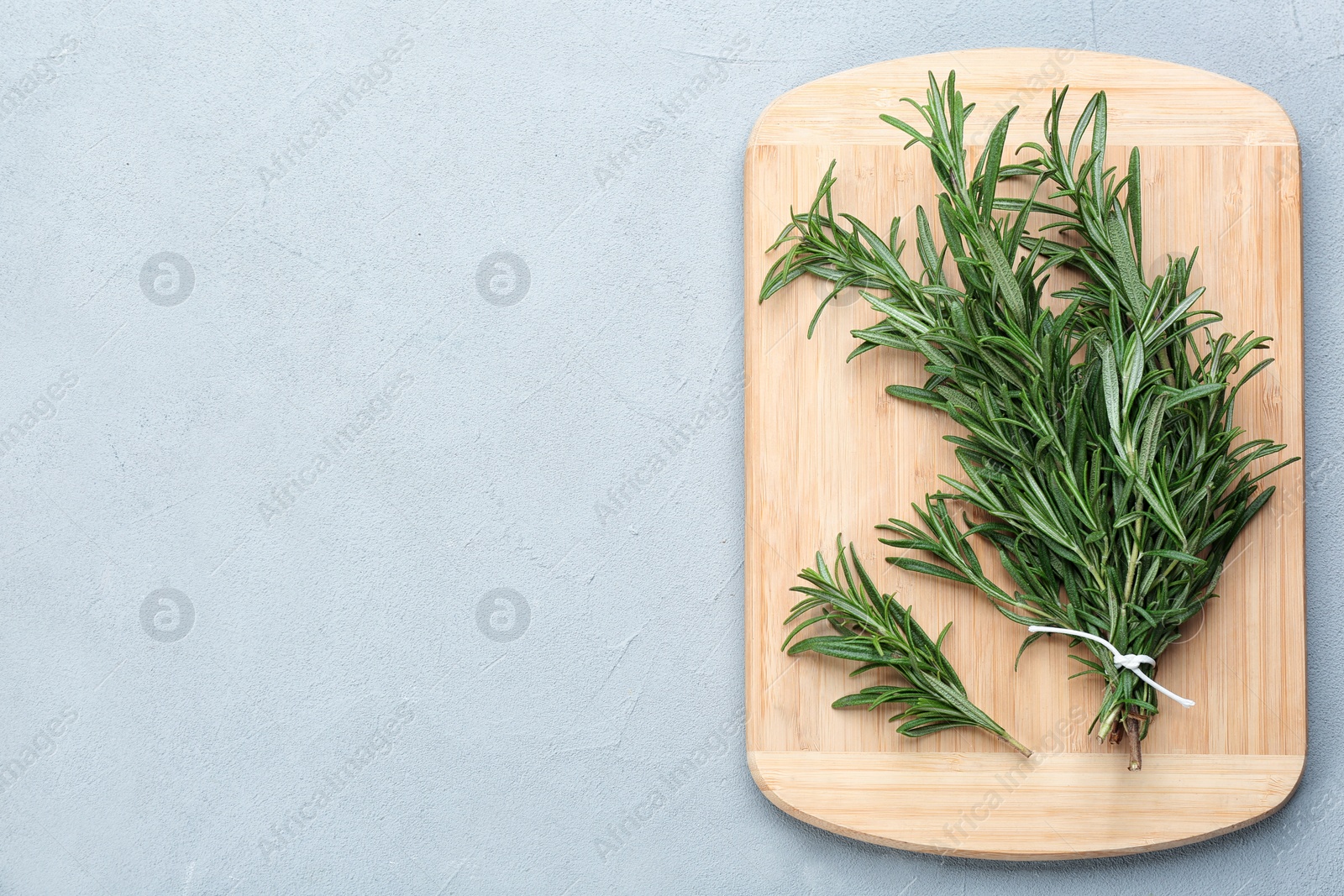 Photo of Bunch of fresh rosemary on light grey table, top view. Space for text