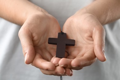 Photo of Woman holding wooden Christian cross, closeup view