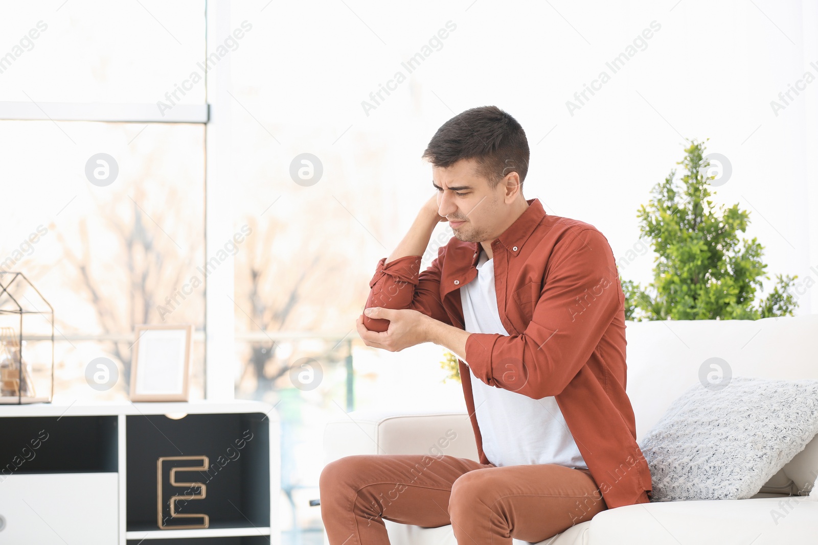 Photo of Young man suffering from elbow pain at home