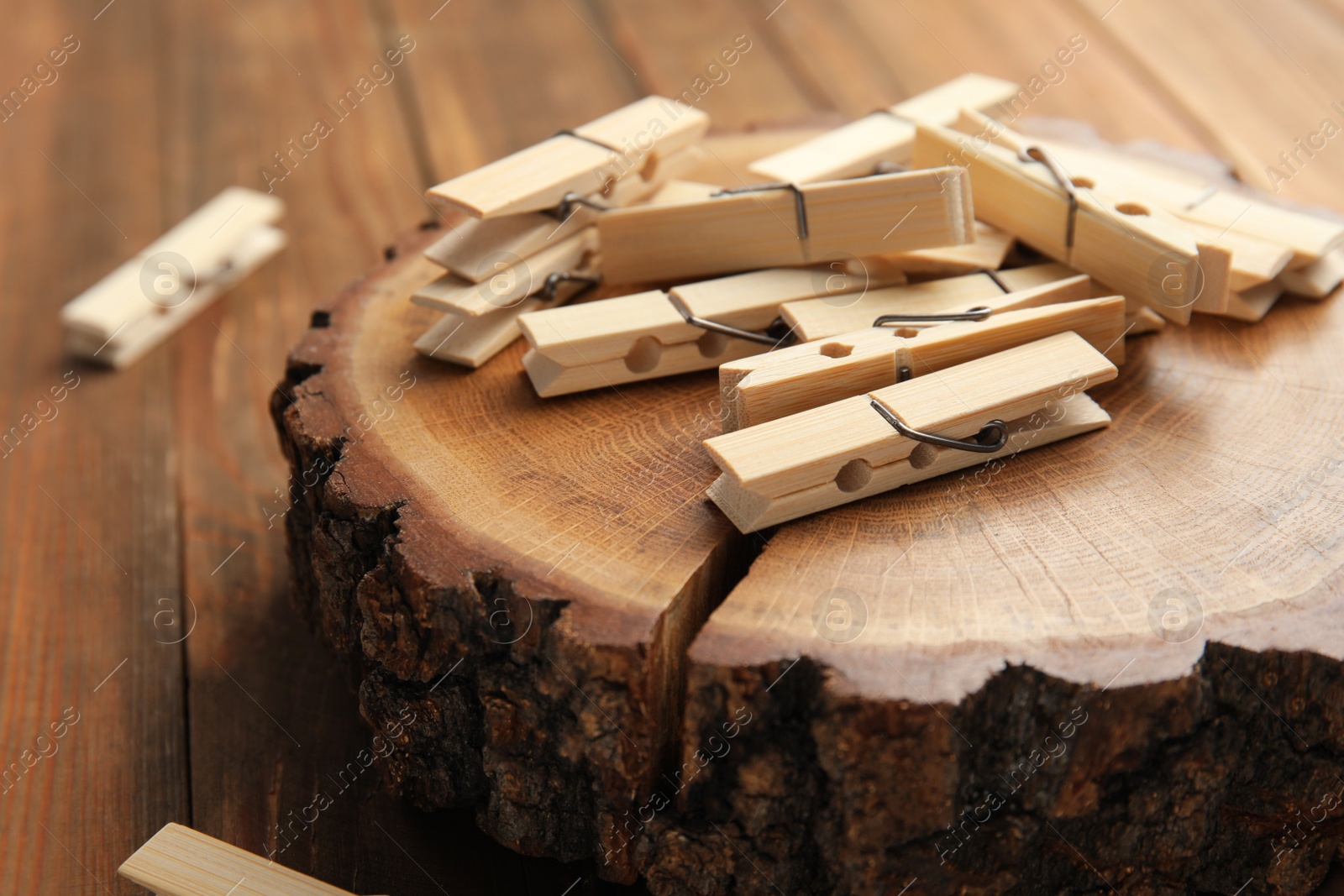 Photo of Many wooden clothespins and decorative stump on table, closeup