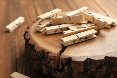 Photo of Many wooden clothespins and decorative stump on table, closeup