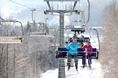 People using chairlift at mountain ski resort. Winter vacation