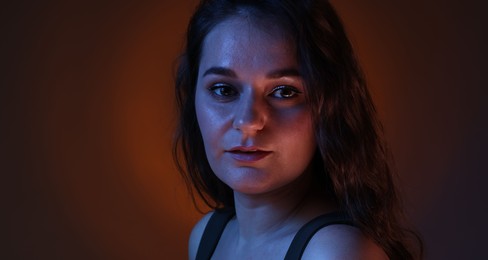 Portrait of beautiful young woman on color background with neon lights