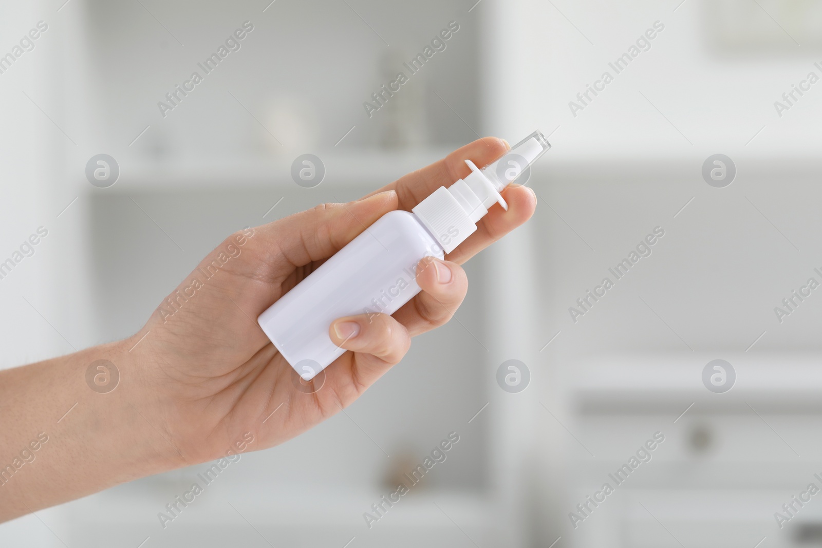 Photo of Woman holding nasal spray bottle indoors, closeup