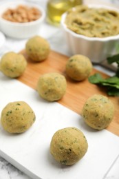 Photo of Board with raw falafel balls on white table, closeup