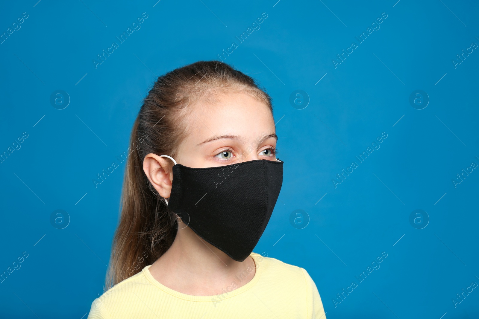 Photo of Preteen girl in protective face mask on blue background