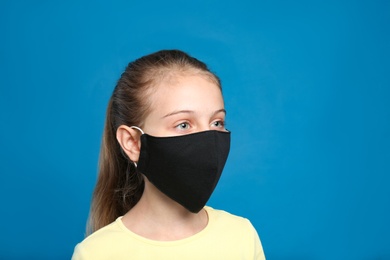 Photo of Preteen girl in protective face mask on blue background