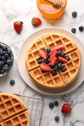 Tasty Belgian waffles with fresh berries and honey on white marble table, flat lay