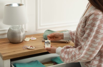 Photo of Woman putting scented sachet into drawer with clothes, closeup