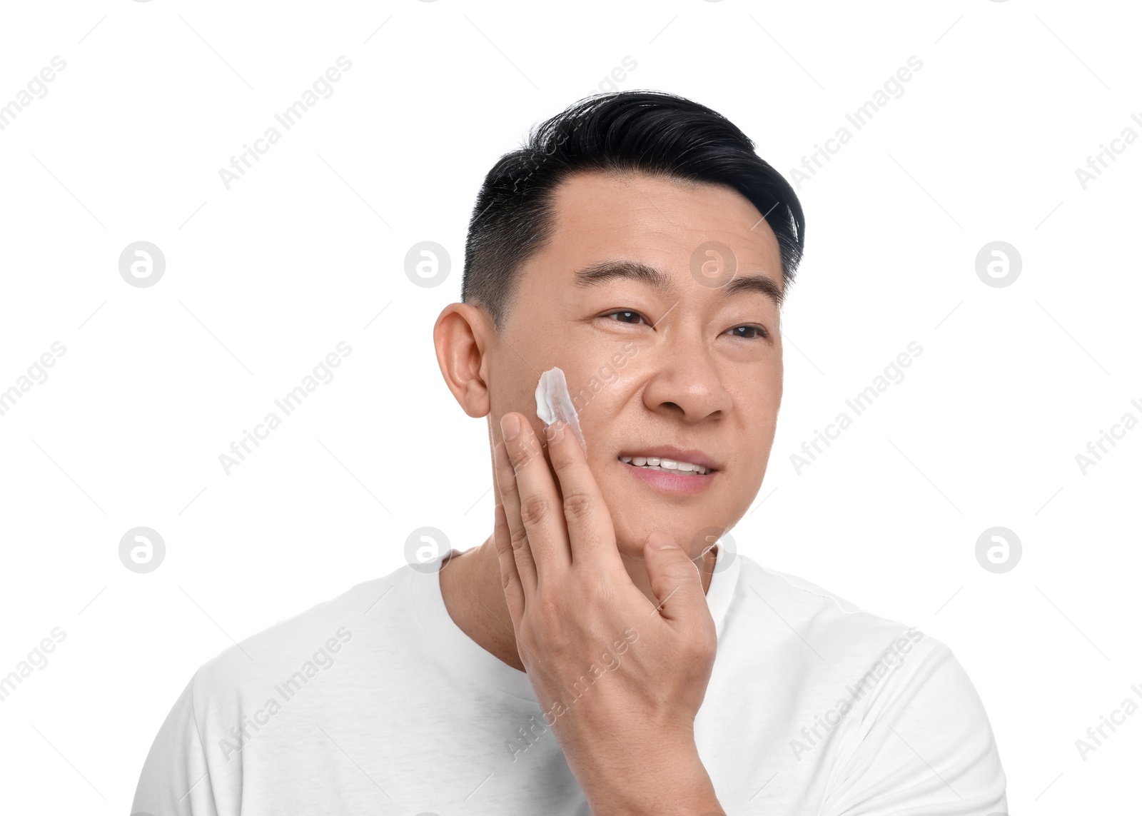 Photo of Handsome man applying cream onto his face on white background