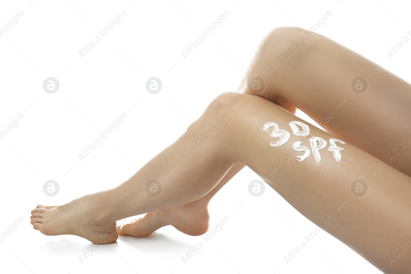 Photo of Text 30 SPF written with sun protection cream on woman's leg against white background, closeup