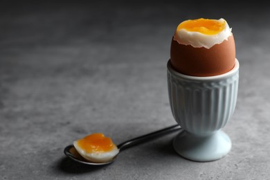 Fresh soft boiled egg in cup on grey table. Space for text