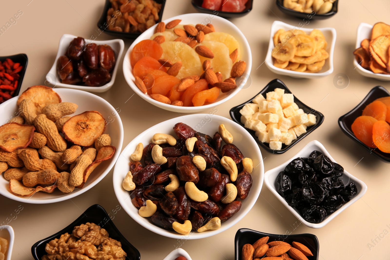 Photo of Bowls with dried fruits and nuts on beige background