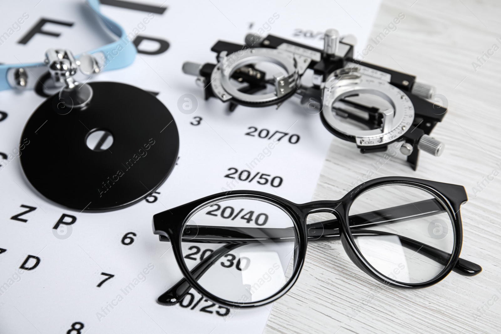 Photo of Different ophthalmologist tools on white wooden table