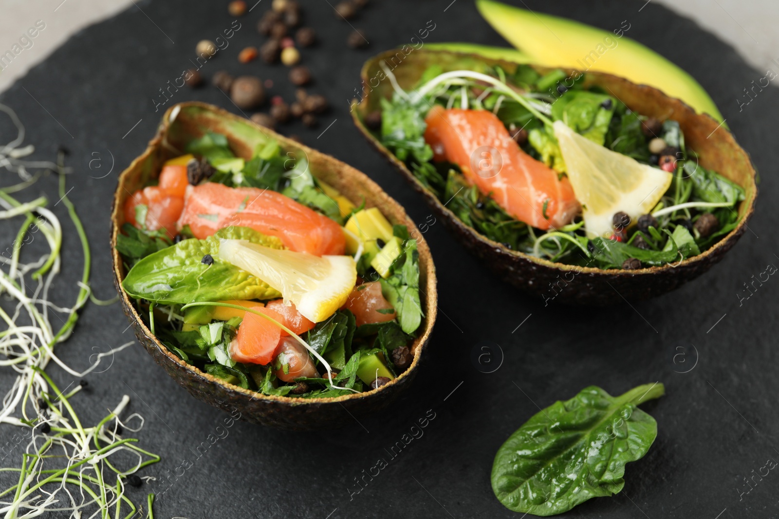 Photo of Delicious salmon with spinach served on slate board, closeup