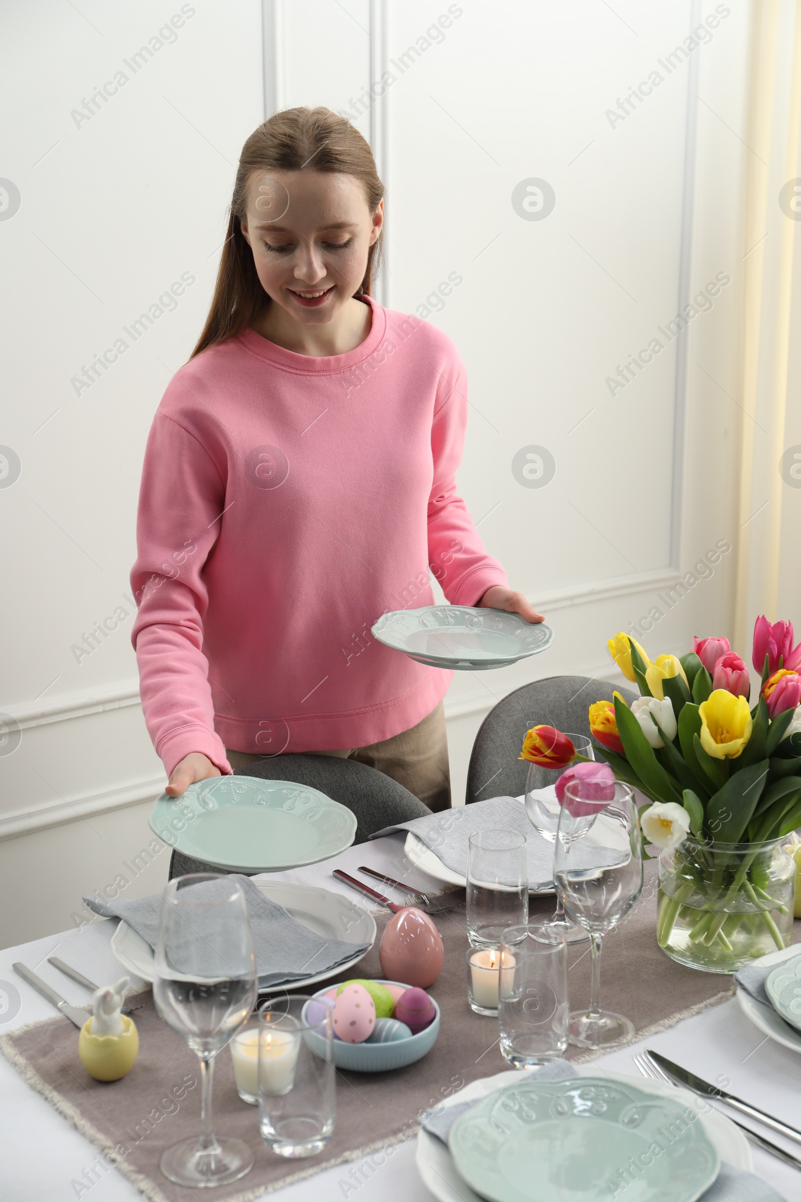 Photo of Woman setting table for festive Easter dinner at home