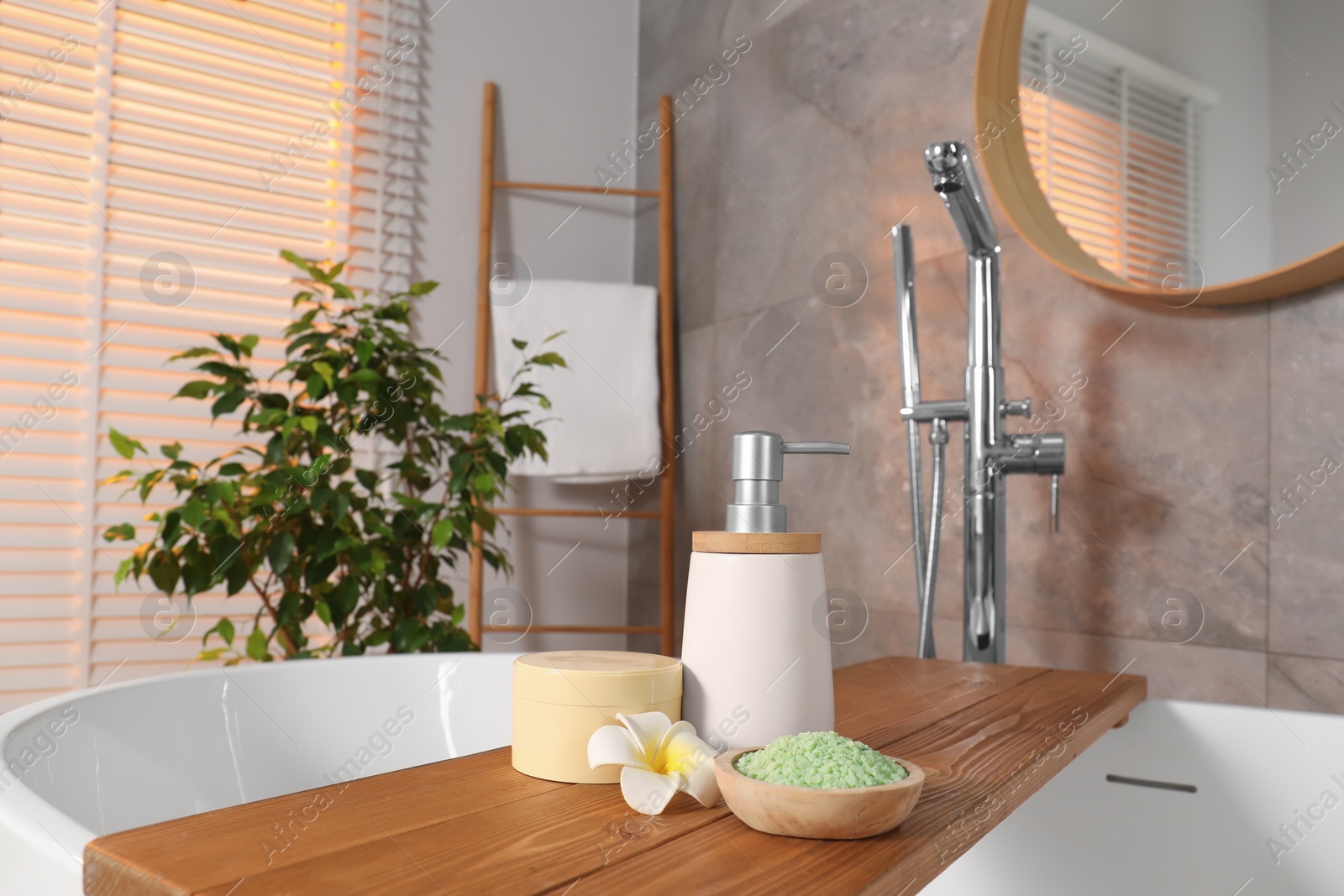 Photo of Spa products and beautiful flower on wooden tub tray in bathroom