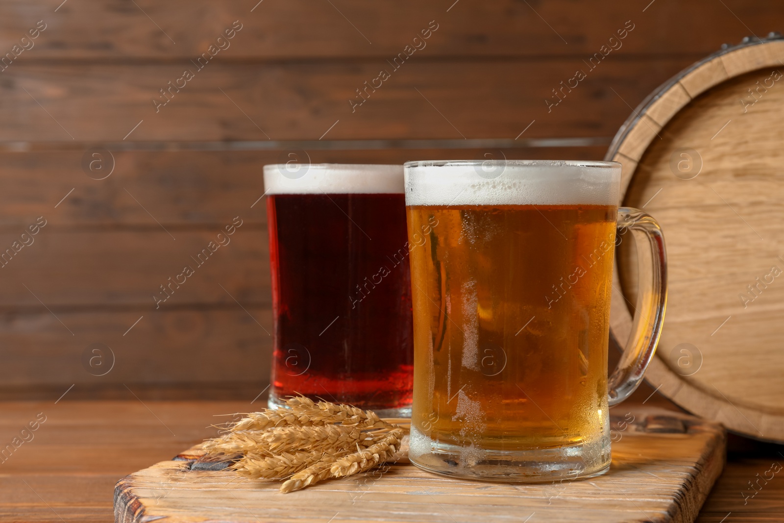 Photo of Glass mugs with different types of cold tasty beer on wooden table