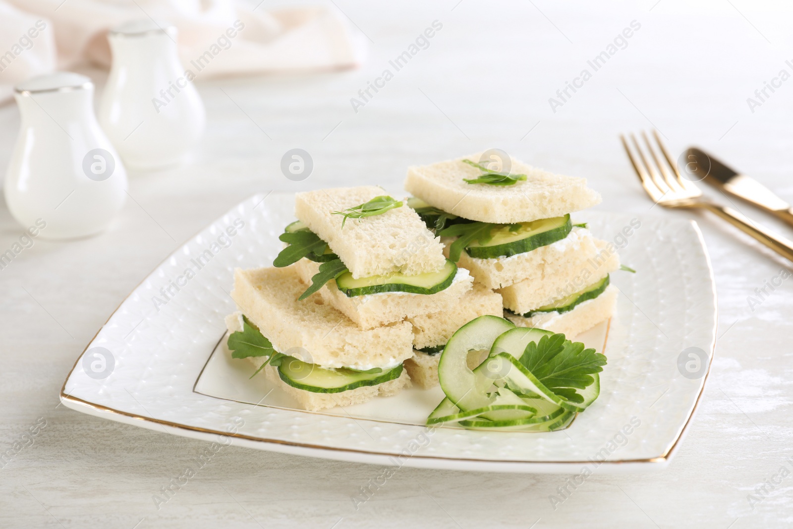 Photo of Plate with tasty cucumber sandwiches served on table