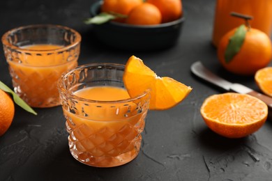 Tasty tangerine liqueur in glasses and fresh citrus fruits on black textured table
