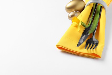 Photo of Cutlery set, Easter eggs and narcissus on white background, space for text. Festive table setting