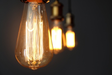 Pendant lamps with light bulbs on grey background, closeup. Space for text