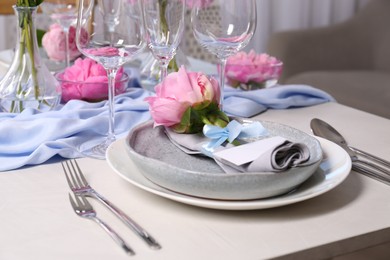 Stylish table setting with beautiful peonies, napkin and blank card indoors