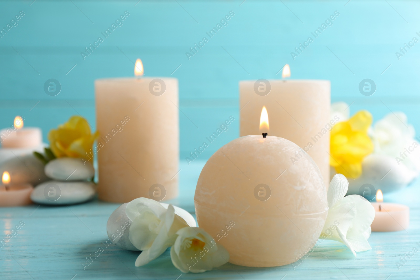 Photo of Burning candles, spa stones and flowers on table. Space for text