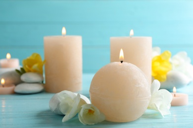 Burning candles, spa stones and flowers on table. Space for text