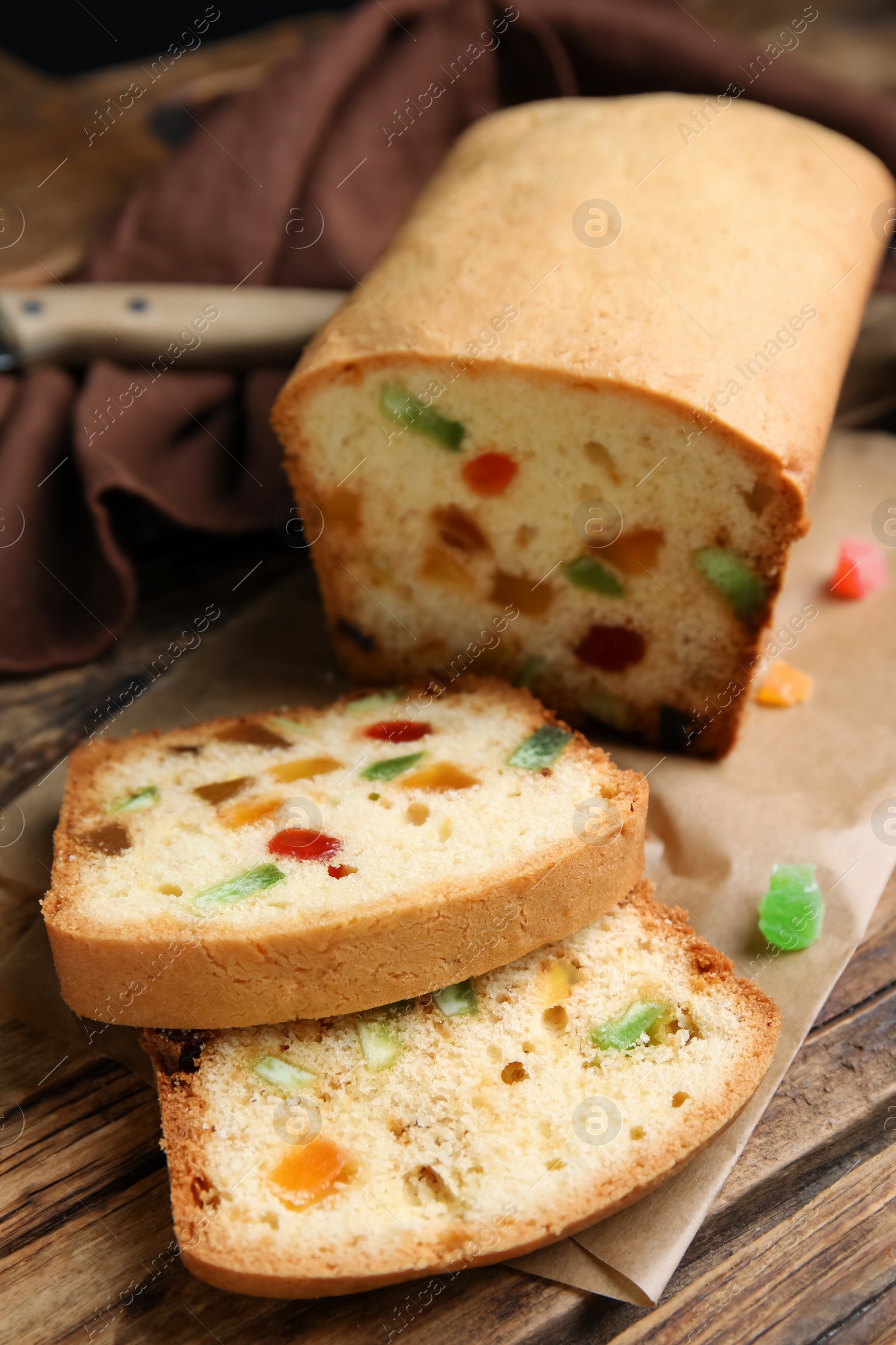 Photo of Delicious cake with candied fruits on wooden table, closeup