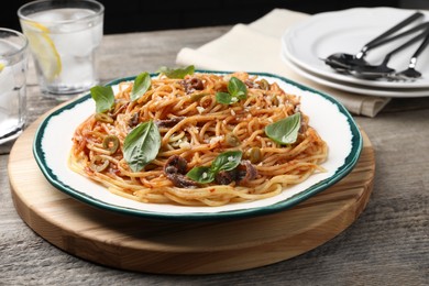 Delicious pasta with anchovies, tomato sauce and basil on wooden table