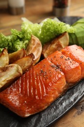 Photo of Tasty cooked salmon and vegetables served on wooden table, closeup. Healthy meals from air fryer
