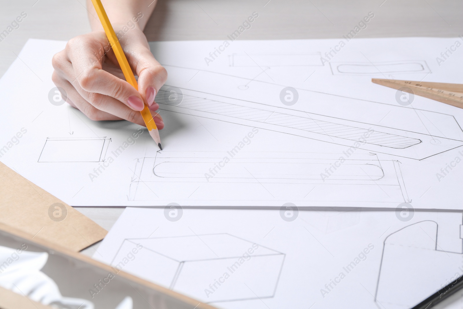 Photo of Woman creating packaging design at light wooden table, closeup