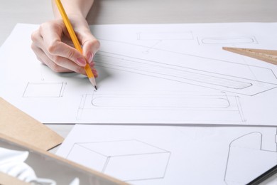 Woman creating packaging design at light wooden table, closeup