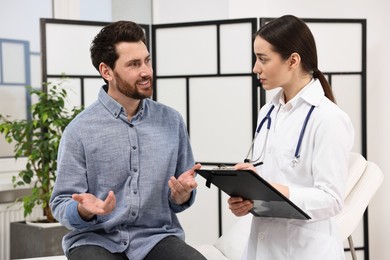 Doctor with clipboard consulting patient during appointment in clinic