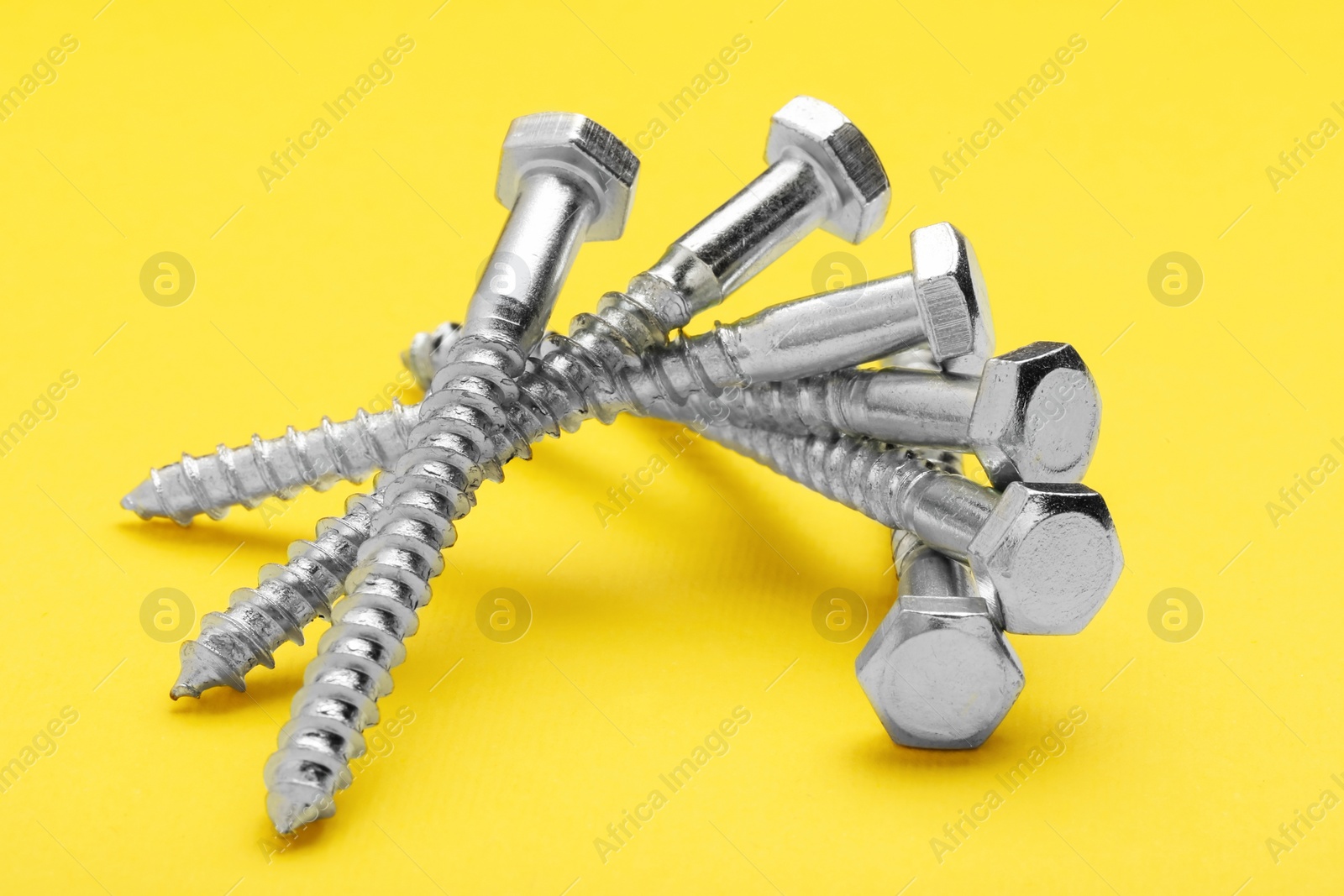 Photo of Many metal self-tapping screws on yellow background