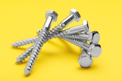 Photo of Many metal self-tapping screws on yellow background