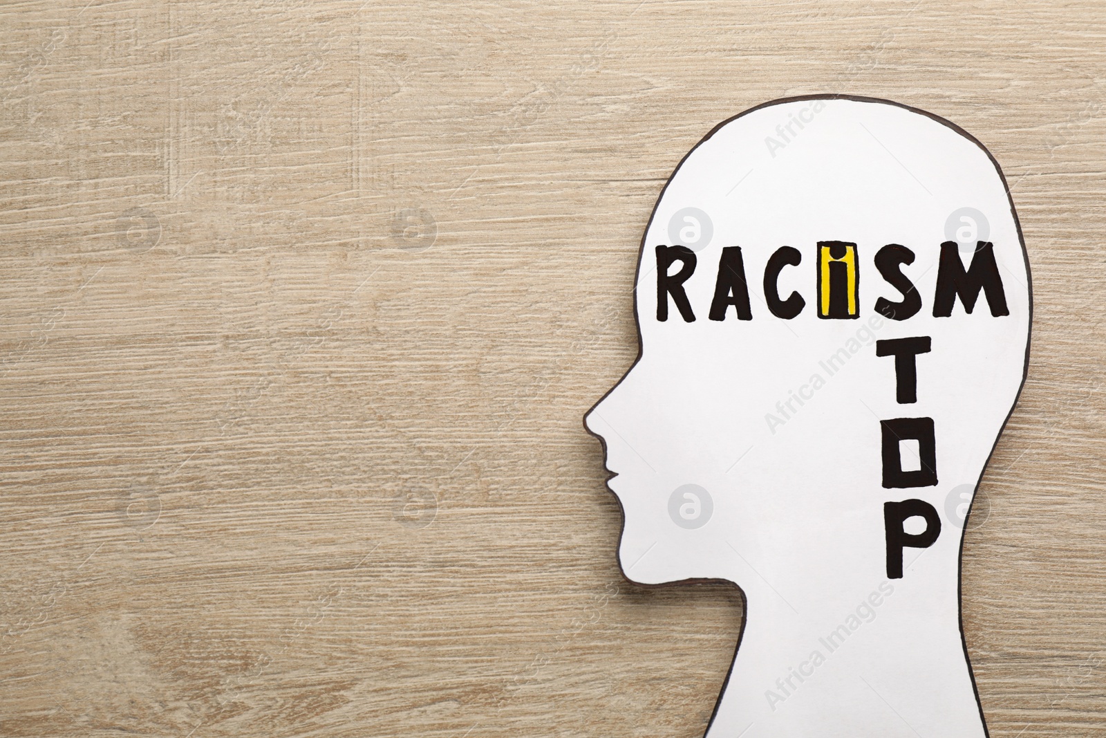 Photo of White head cutout with phrase Stop Racism on wooden table, top view. Space for text