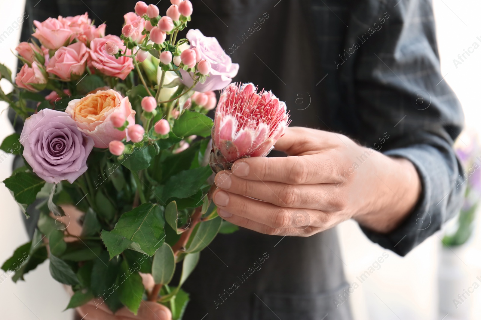 Photo of Male florist holding beautiful bouquet, closeup