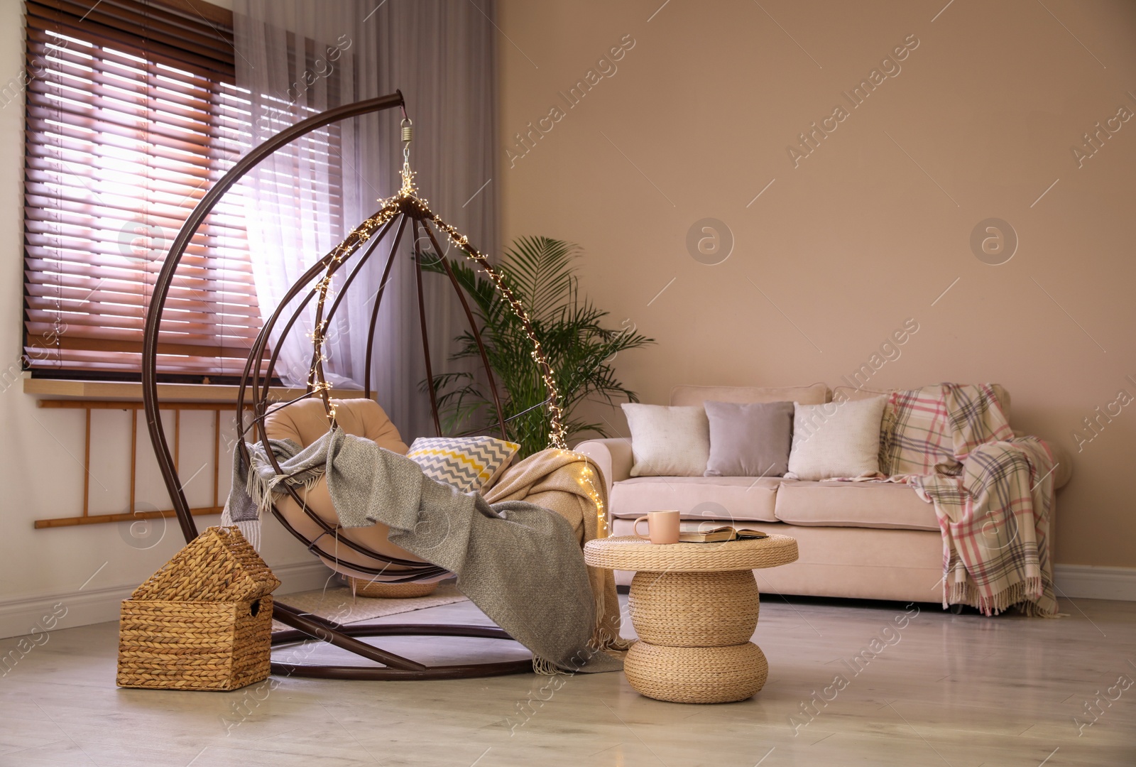 Photo of Cozy hanging chair with fairy lights in modern living room. Interior design