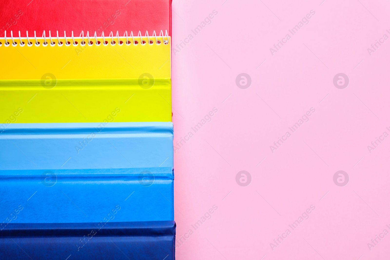 Photo of Bright notebooks  and space for text on pink background, flat lay. Rainbow colors