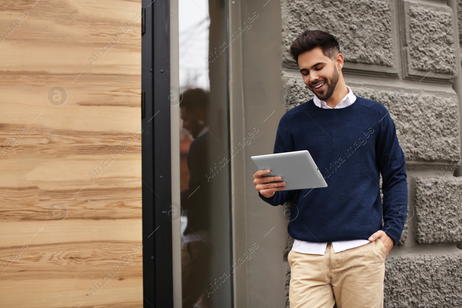 Photo of Young male business owner with tablet near his cafe. Space for text