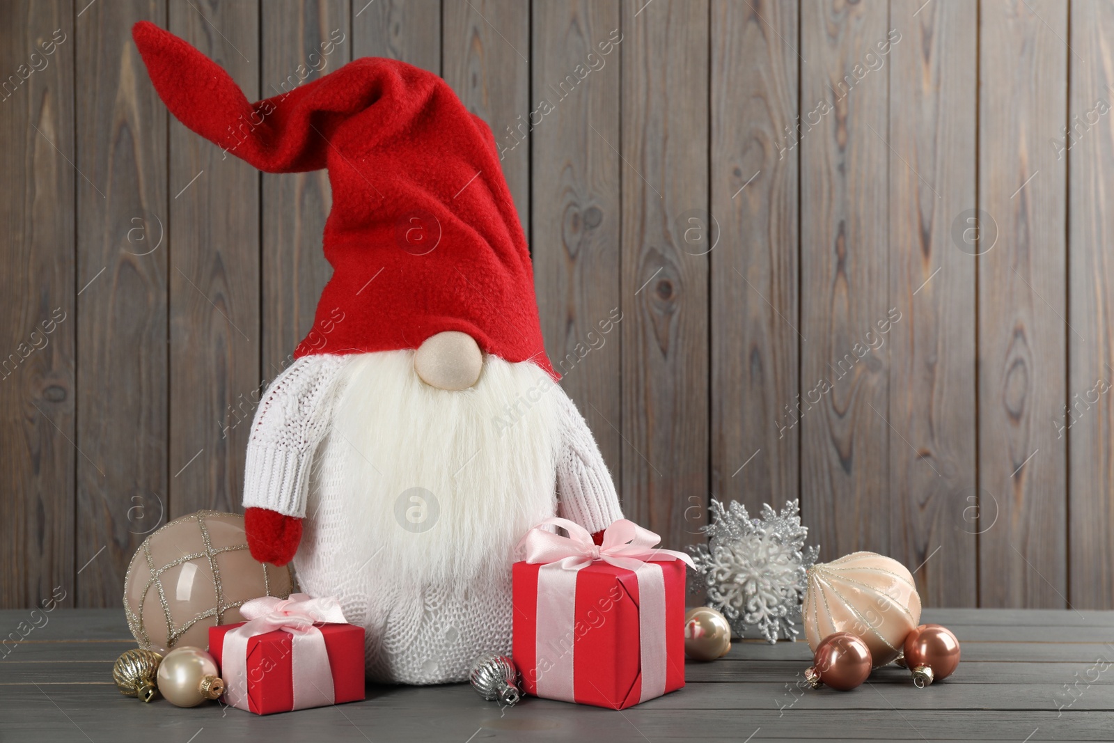 Photo of Cute Christmas gnome, gift boxes and festive decor on wooden table. Space for text