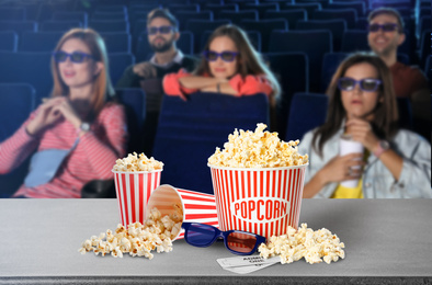 Popcorn, 3D glasses on table and young people in cinema hall