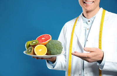Photo of Nutritionist with healthy products on blue background, closeup