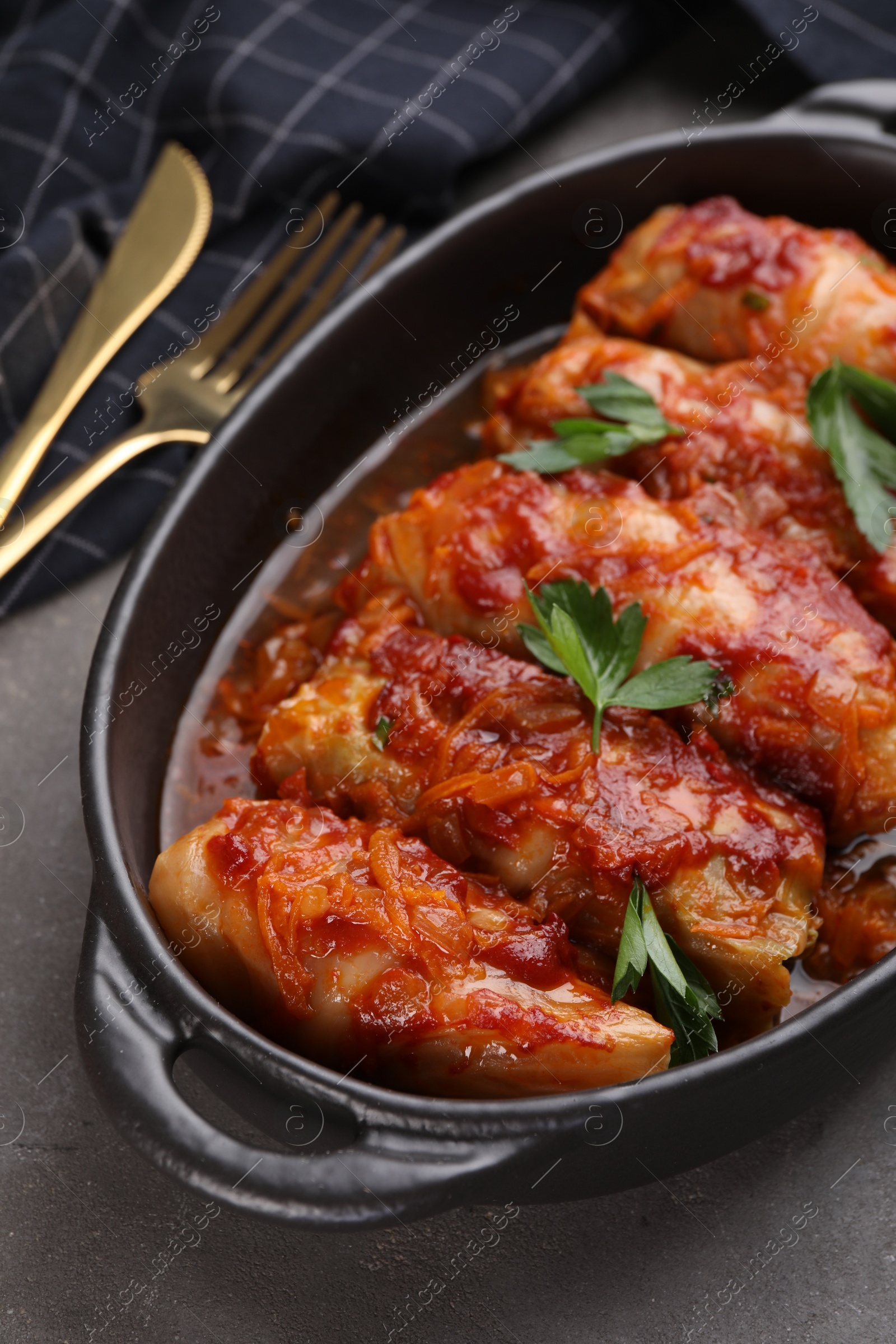 Photo of Delicious stuffed cabbage rolls cooked with tomato sauce on grey table, closeup