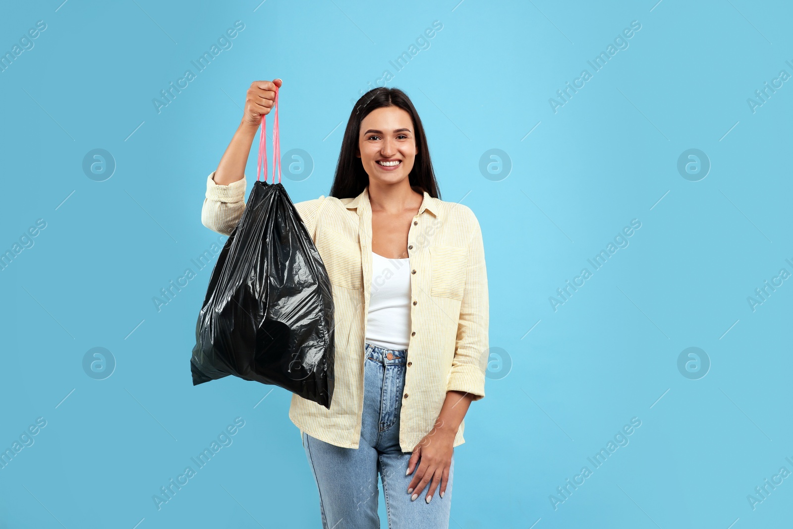 Photo of Woman holding full garbage bag on light blue background