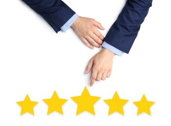 Image of Quality evaluation. Businessman pointing at virtual golden stars on white background, closeup